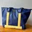 Blue tote bag made from upcycled airline seats with yellow details of pineapple fiber leather.