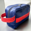 A blue upcycled toiletry bag with red pineapple-leather details.