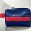 A blue sustainable toiletry bag with red pineapple-leather details.
