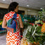 A female wearing a red dress in a fruit store with her upcycled crossbody colourful bag.