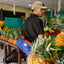 A young man in a fruit store with a pineapple-leather sustainable gym bag.