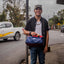 A young man holding a blue upcycled gym bag with colourful details.