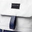 Wearsos Do Good minimalist white upcycled backpack with a navy blue leather-look tab and branded patch